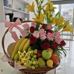 Canasta con frutas frescas, rosas rojas y rosas, y lirios amarillos
