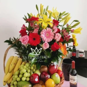 Canasta frutal con flores mixtas en tonos rojos rosas y amarillos