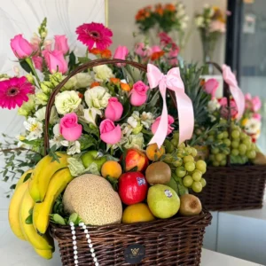 Canasta frutal grande con frutas frescas rosas y flores mixtas en tonos rosa y blanco