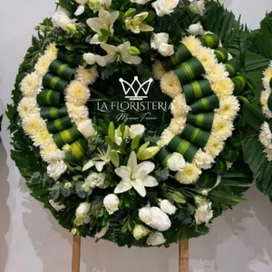 Corona fúnebre blanca de condolencias con rosas, lirios y follaje verde en base circular